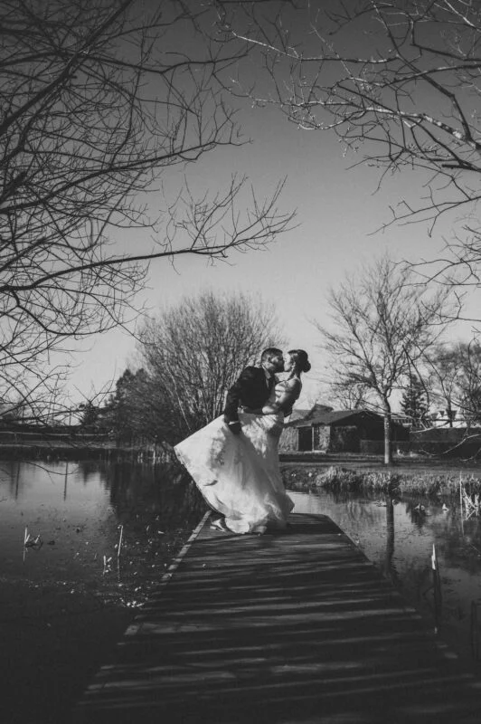 A bride and groom kissing on a dock.