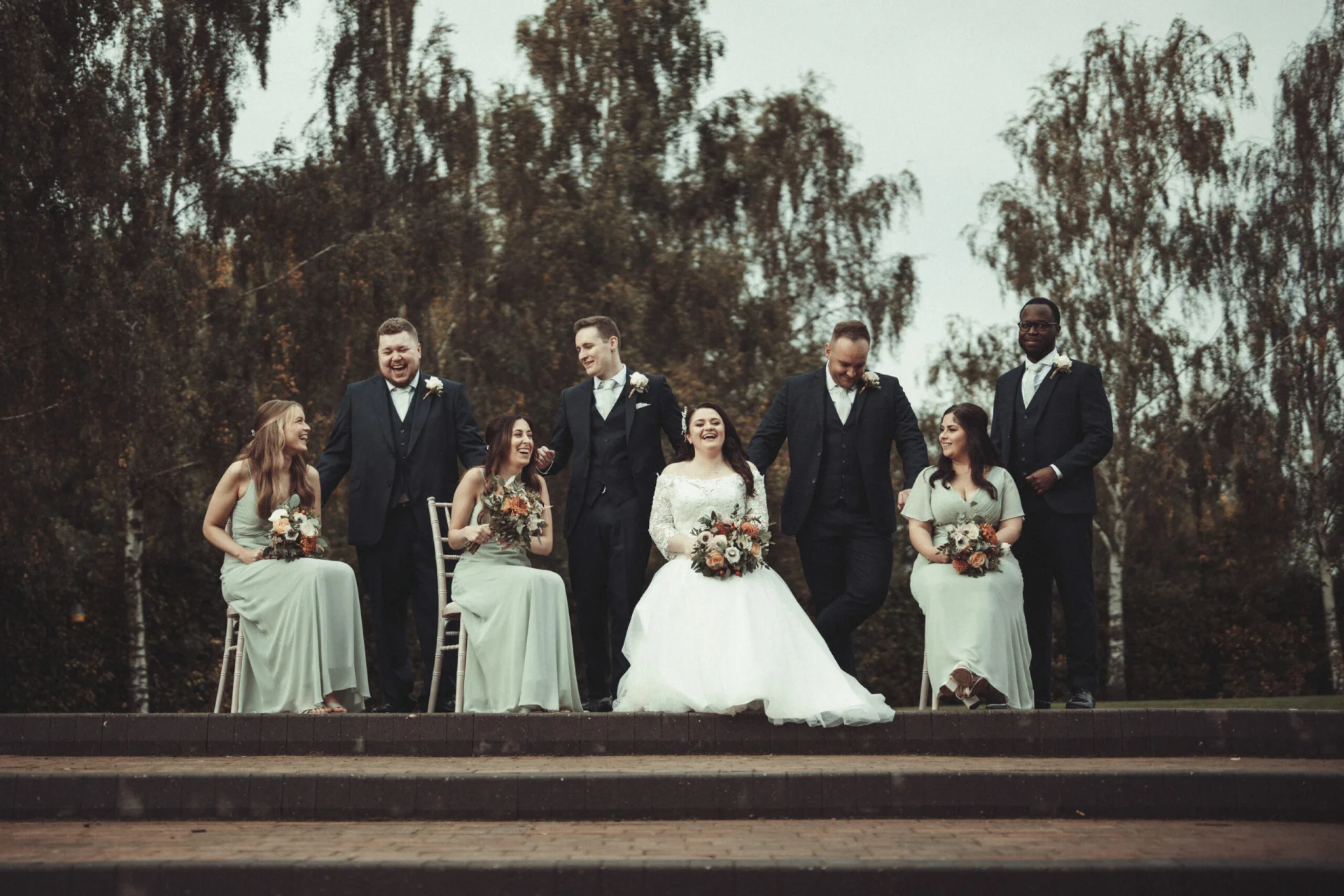 A group of bridesmaids and groomsmen posing for a photo. (listing)