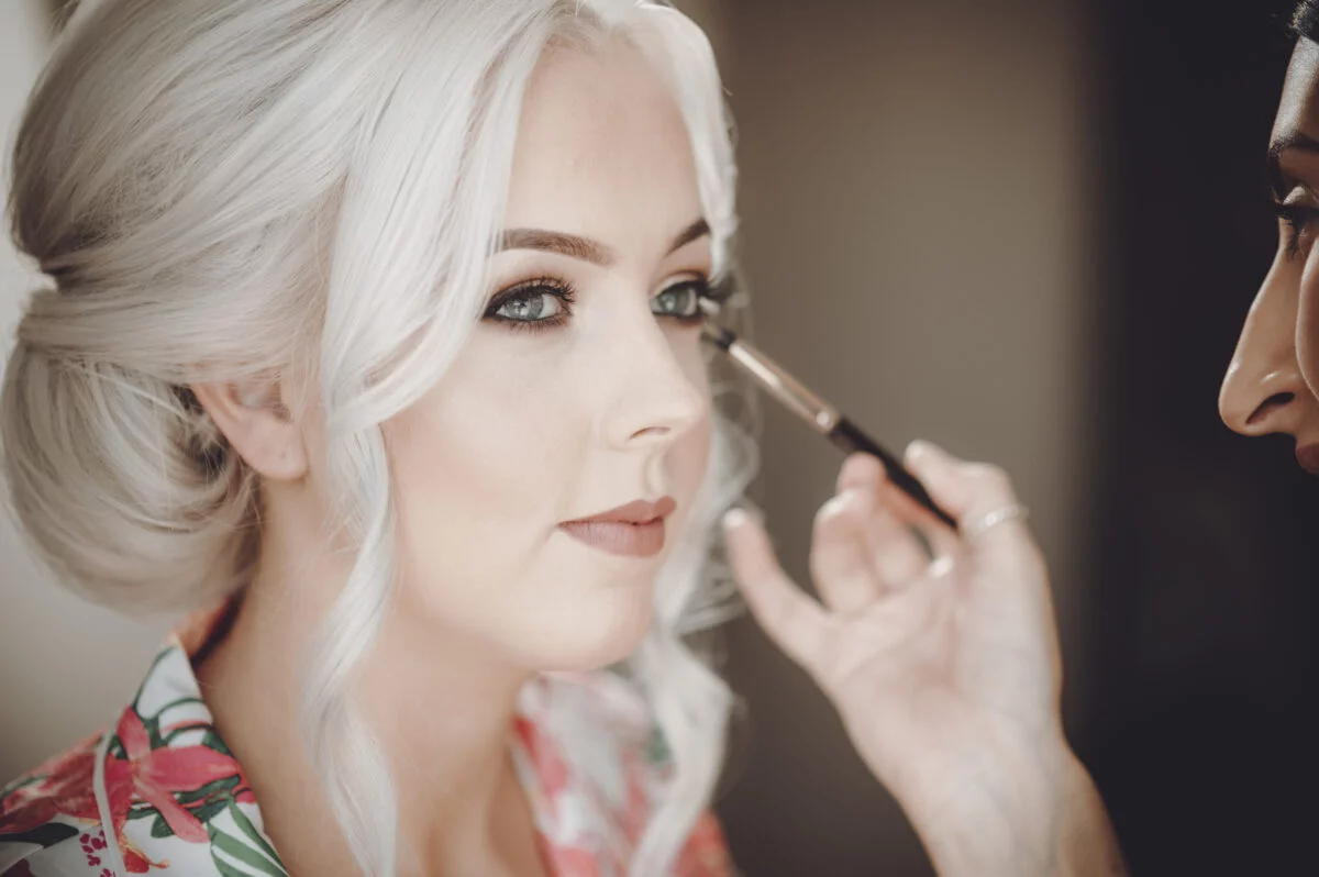 A bride getting her makeup done by a makeup artist.