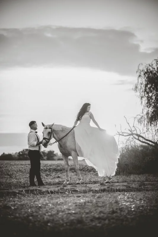 A man and woman in a dress on a horse.