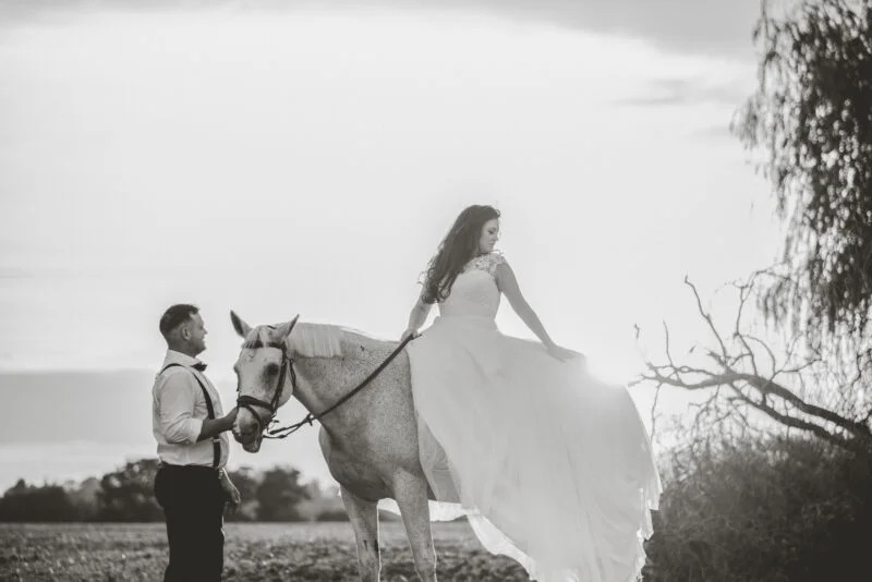 A man and woman in a dress on a horse.