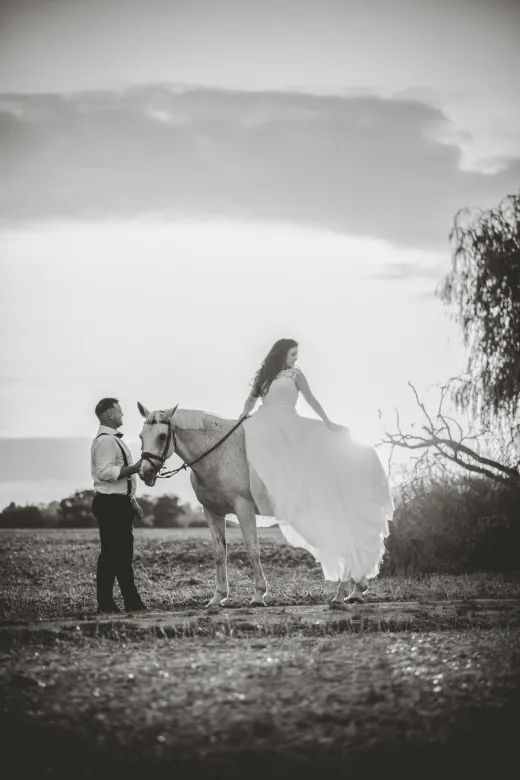 A man and woman in a dress on a horse.