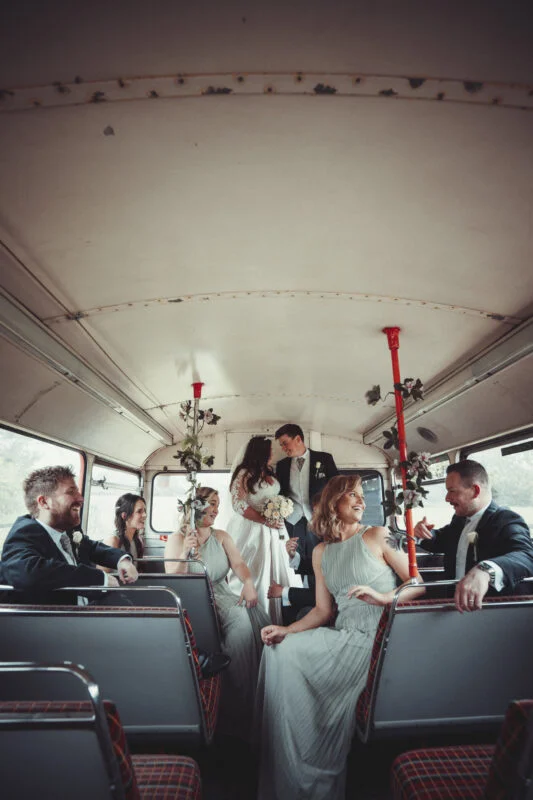 A group of bridesmaids and groomsmen on a bus.