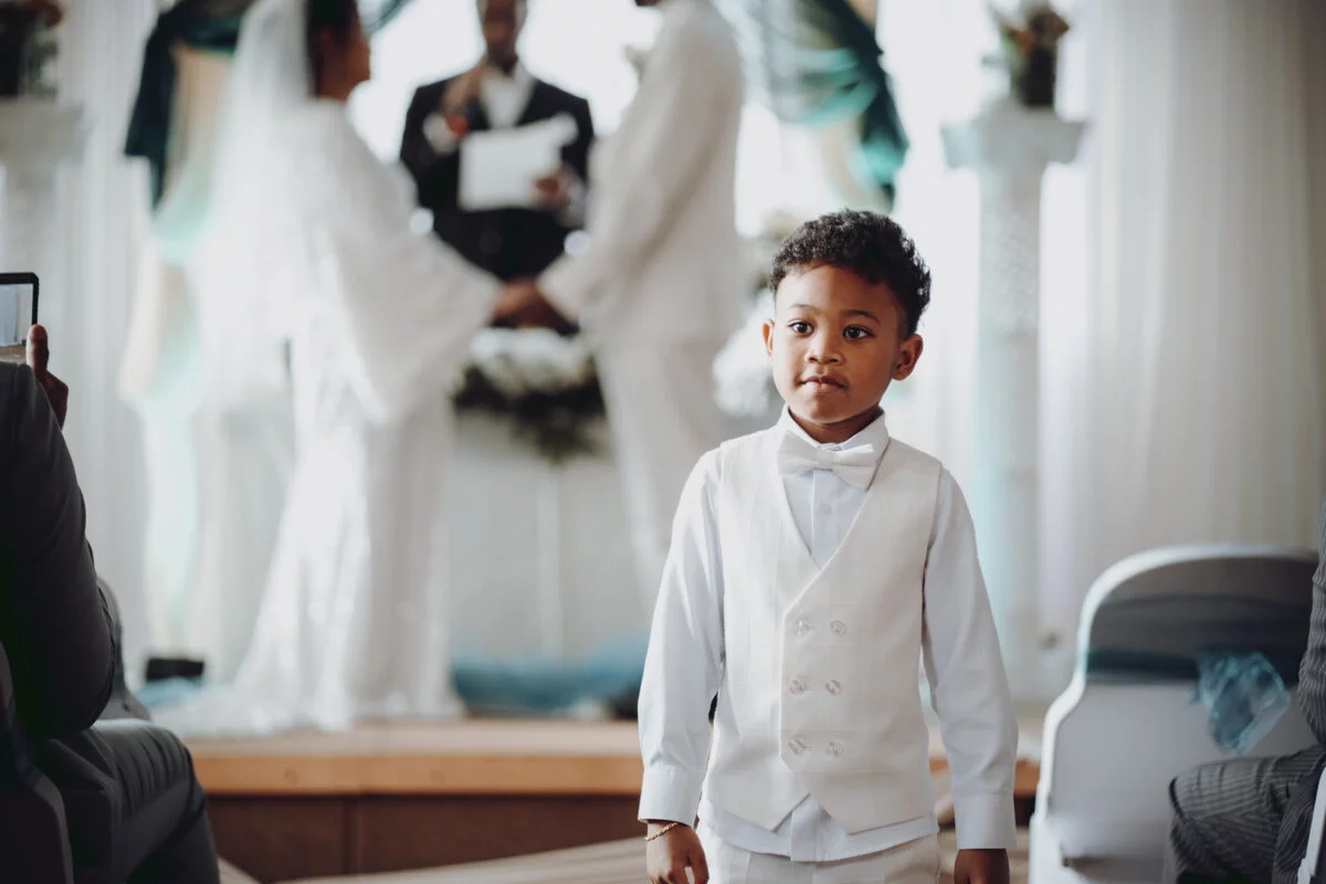 A young boy standing in front of a wedding ceremony.