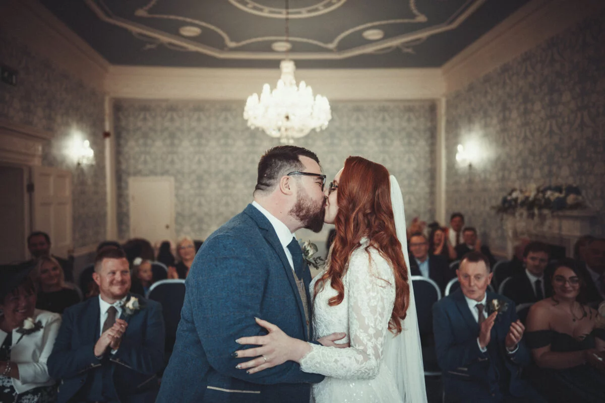 A bride and groom kissing in front of an audience.