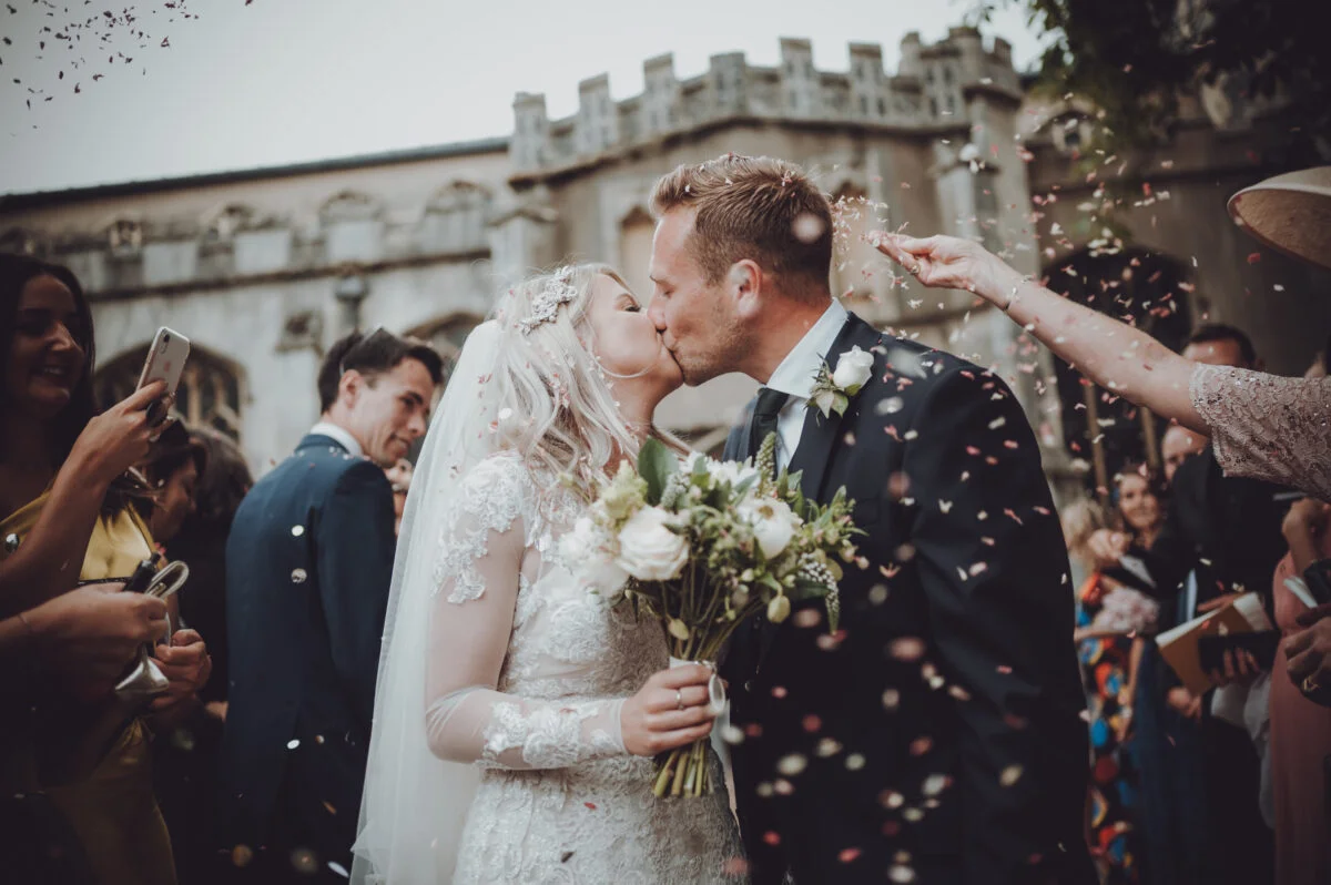 A bride and groom kissing in front of confetti.