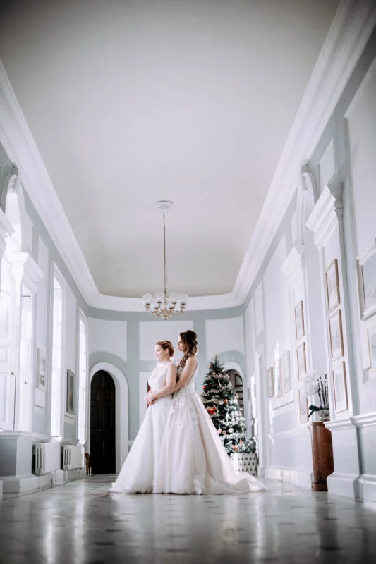 Two brides posing in a large hall.
