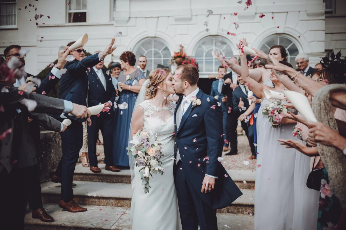 A bride and groom kissing in front of confetti.