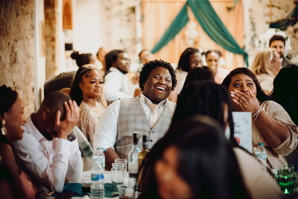A group of people laughing at a wedding reception.