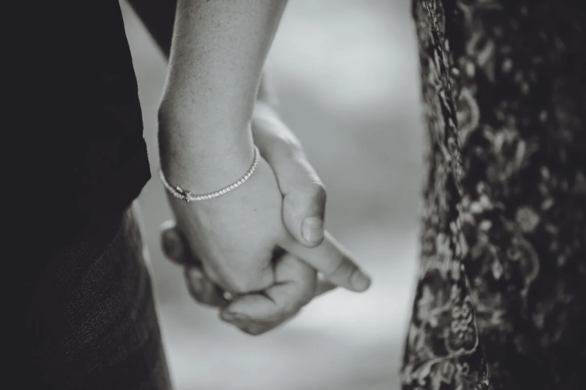 A black and white photo of a couple holding hands.