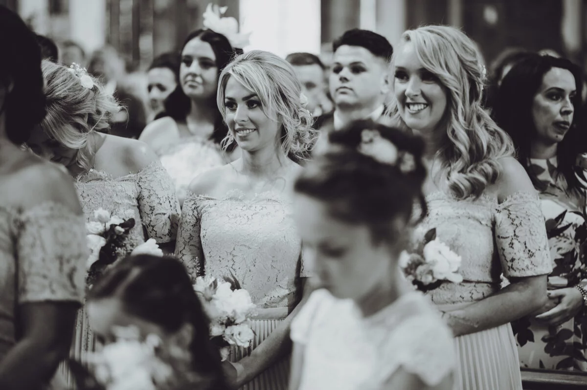 Bridesmaids smiling at each other in a church.