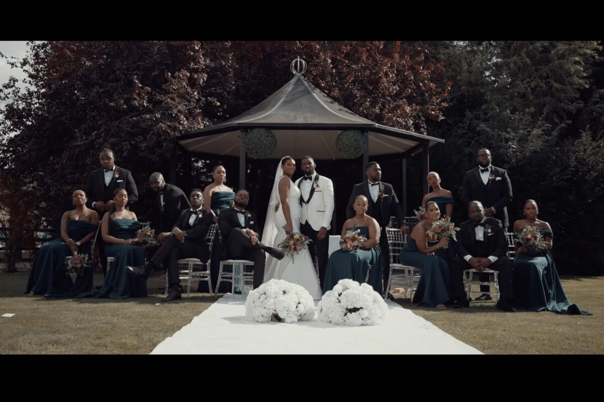 A wedding party posing in front of a gazebo.