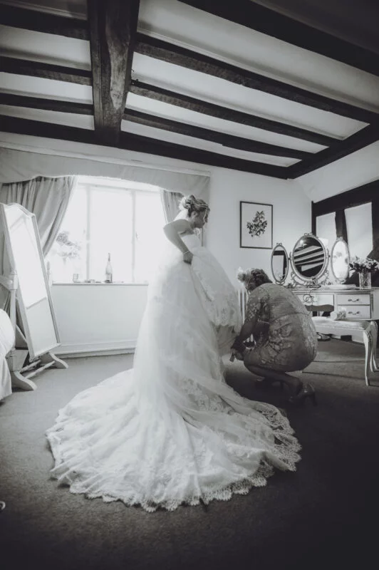A bride putting on her wedding dress in a room.