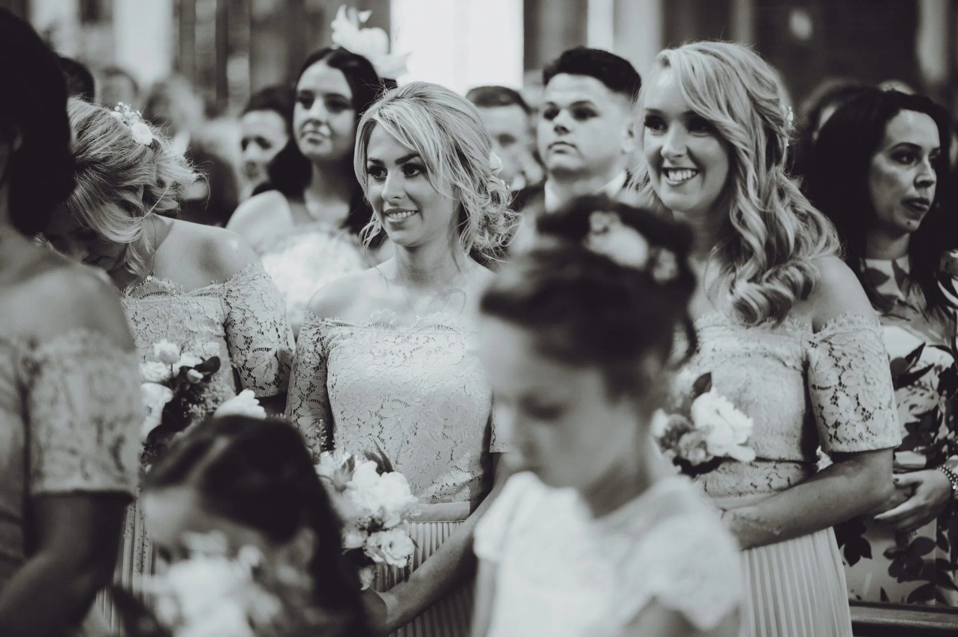Bridesmaids smiling at each other in a church. (listing)
