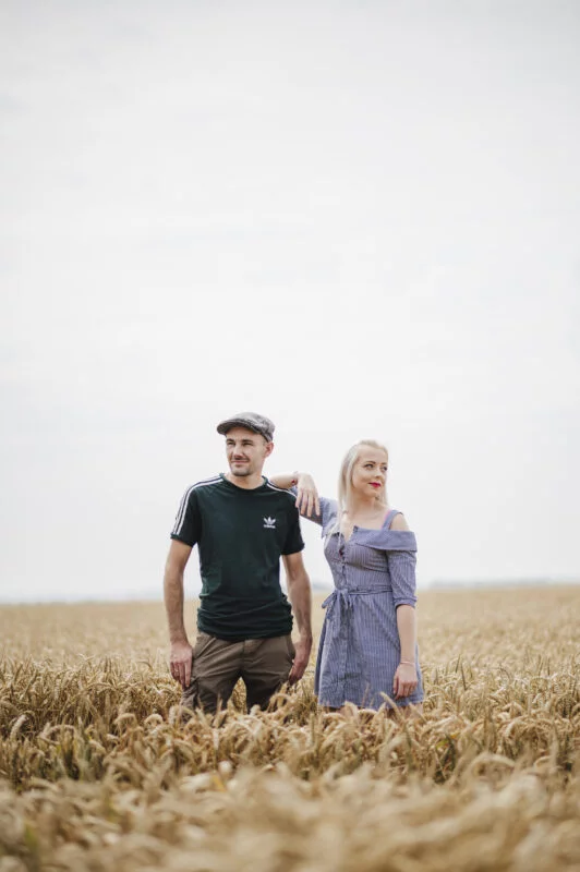 A man and woman standing in a wheat field.