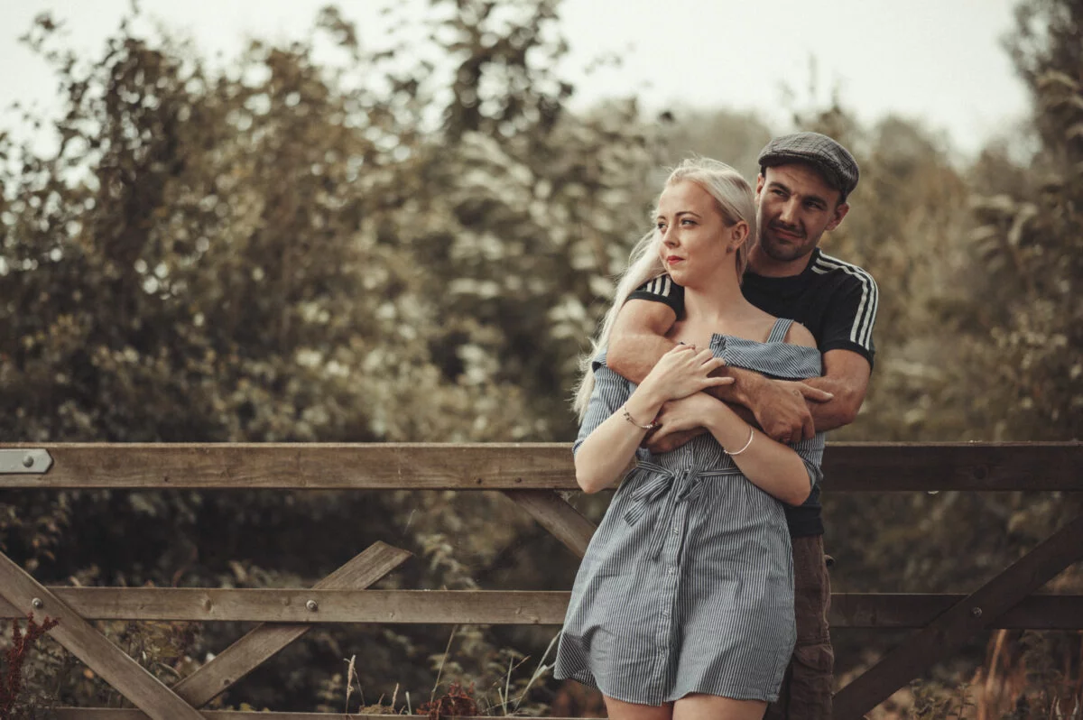 A man and woman hugging on a wooden bridge.