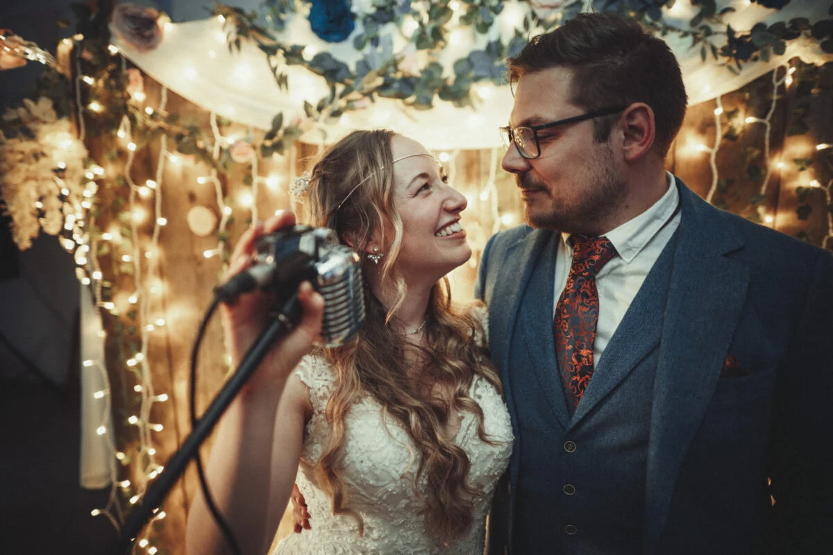 A bride and groom standing in front of a microphone.