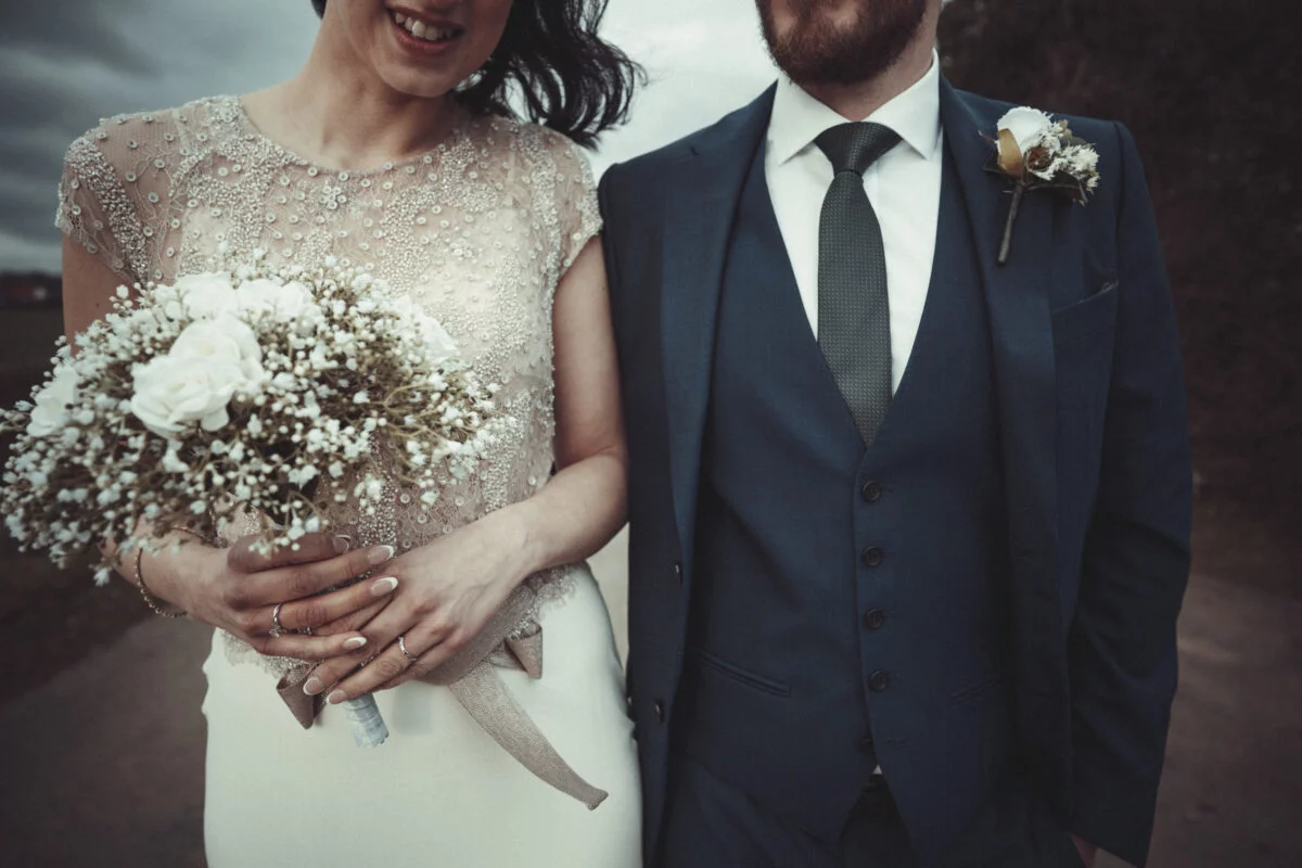 A bride and groom standing next to each other holding a bouquet of baby's breath.