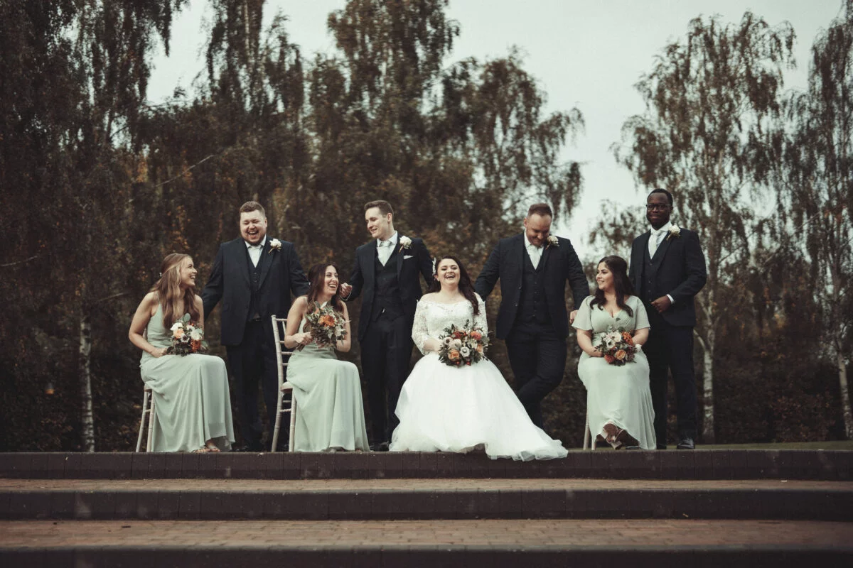 A group of bridesmaids and groomsmen posing on steps.