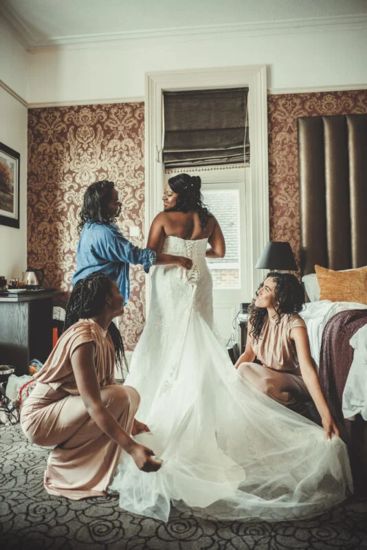 A bride and her bridesmaids are getting ready in a hotel room.