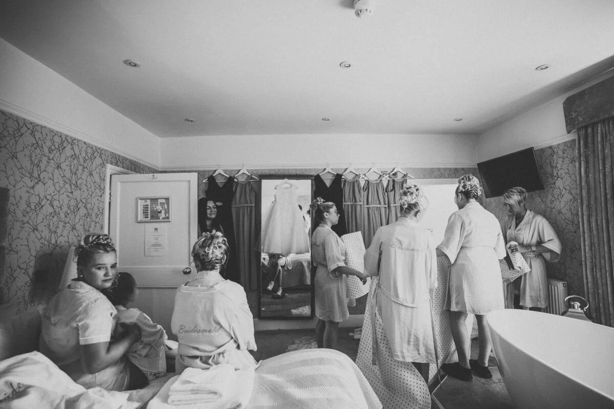 A black and white photo of bridesmaids getting ready in a hotel room.
