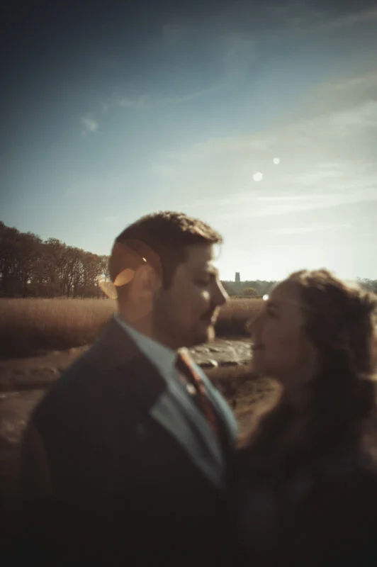 A bride and groom standing in front of a field.