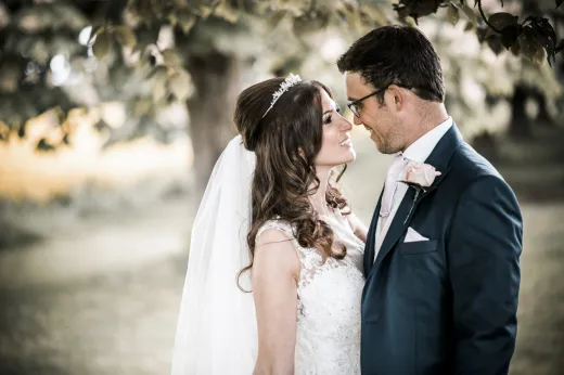 A bride and groom kissing under a tree.