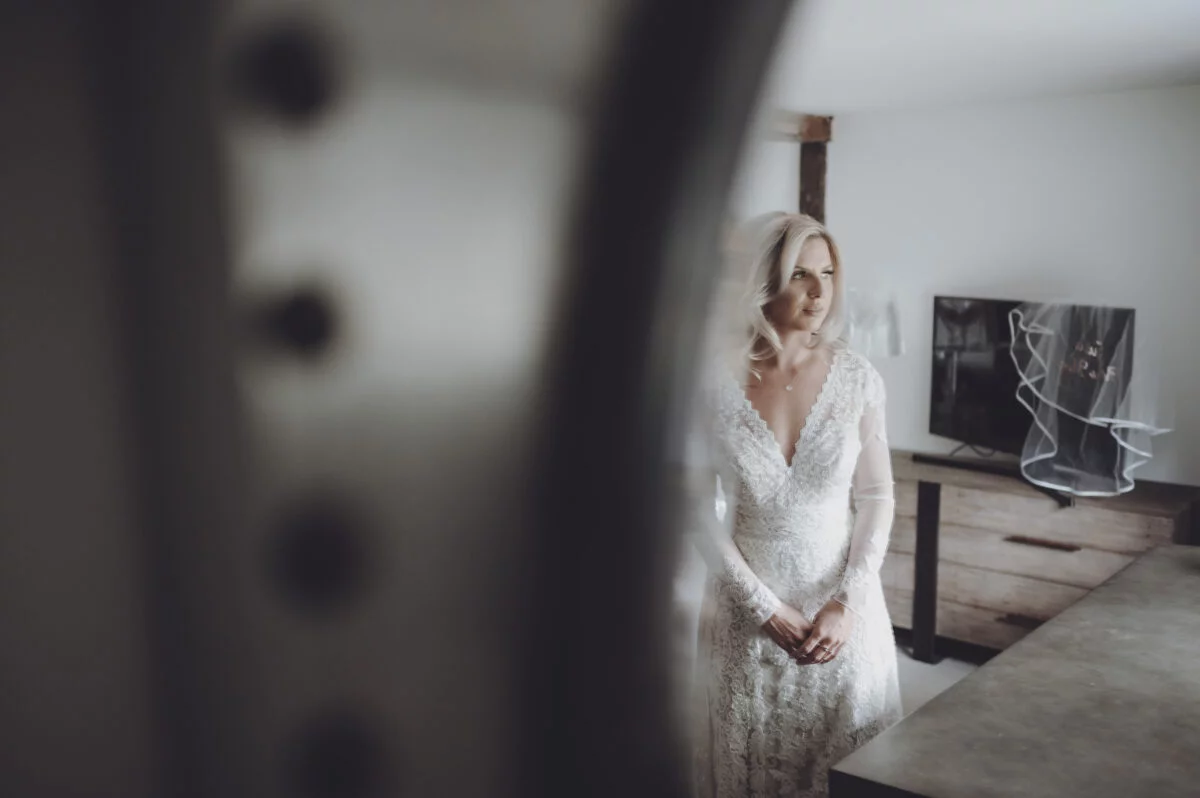A bride in a wedding dress is standing in front of a mirror.
