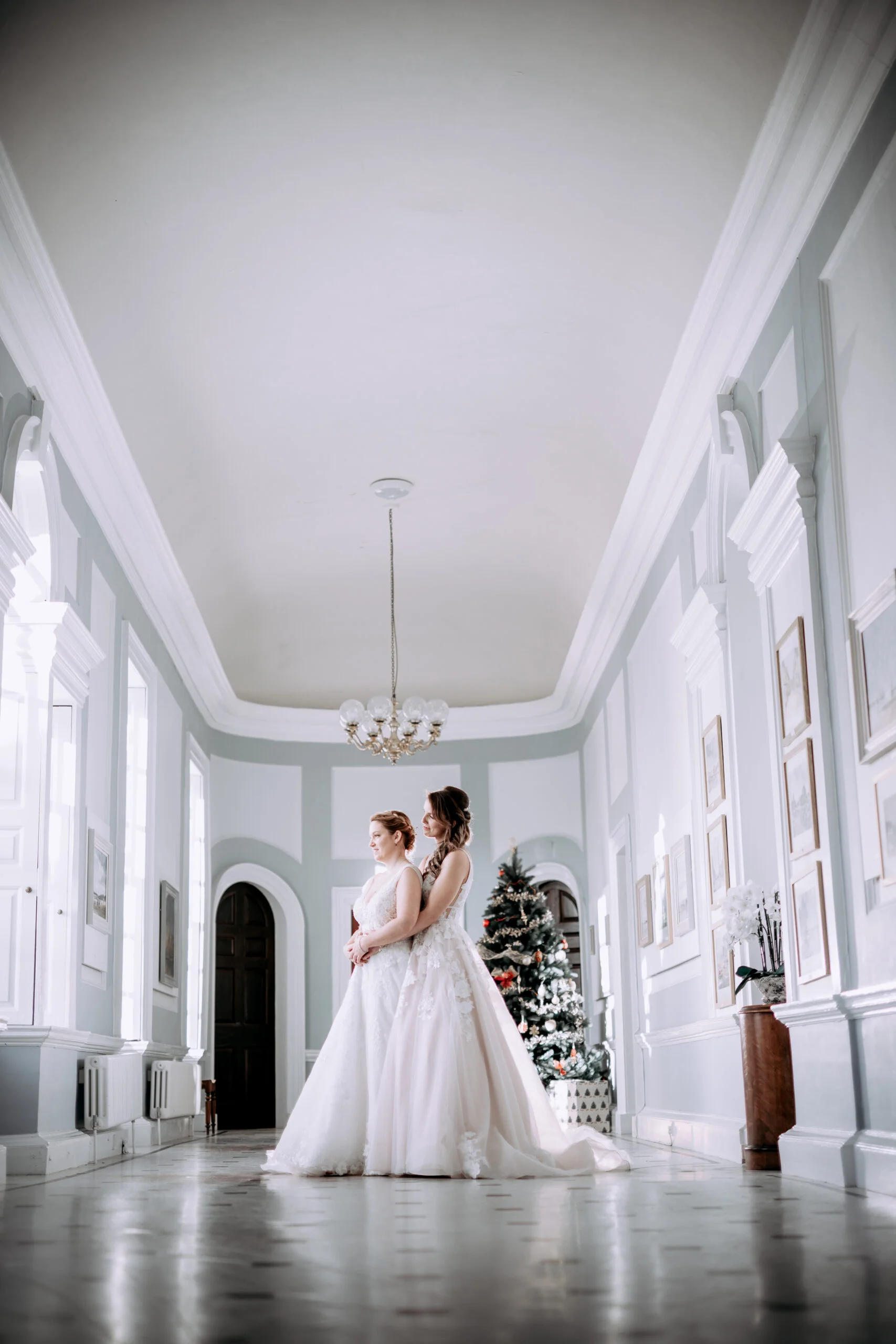 Two brides posing in a large hall. (listing)