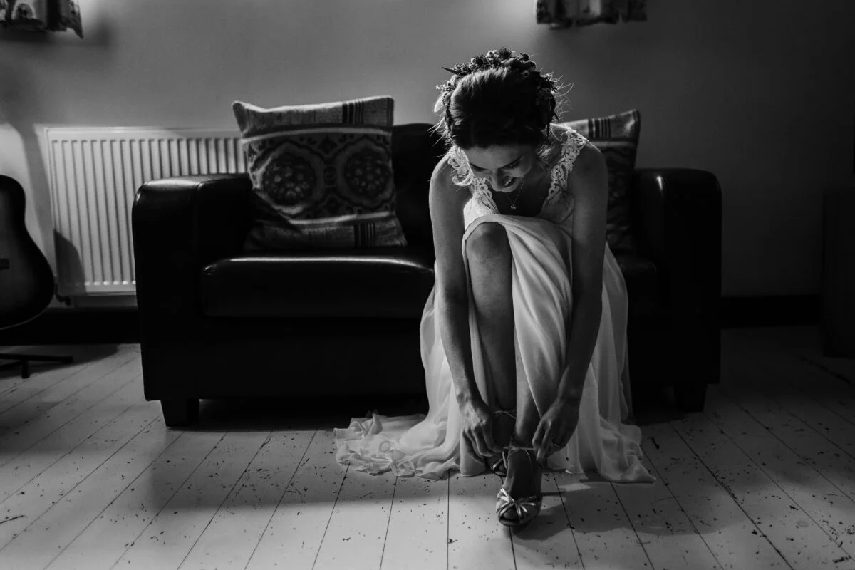 Black and white photo of a bride putting her shoes on.