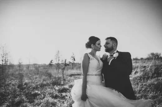 A bride and groom standing in a field.