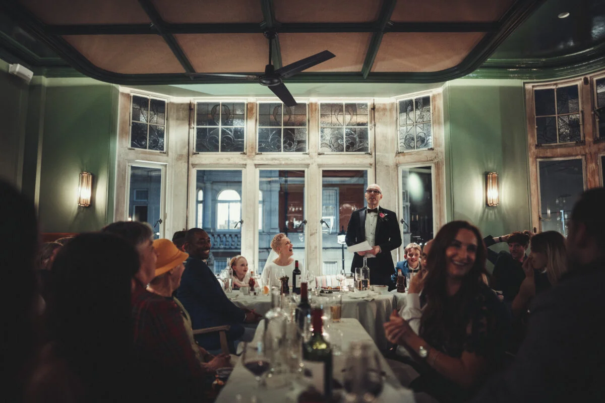 A man speaking to a group of people in a restaurant.