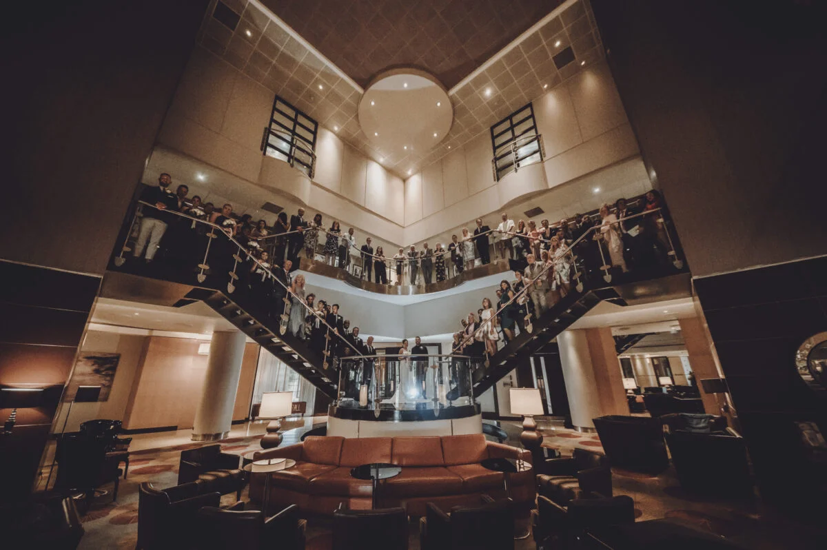 A group of people standing at the top of a staircase in a hotel.