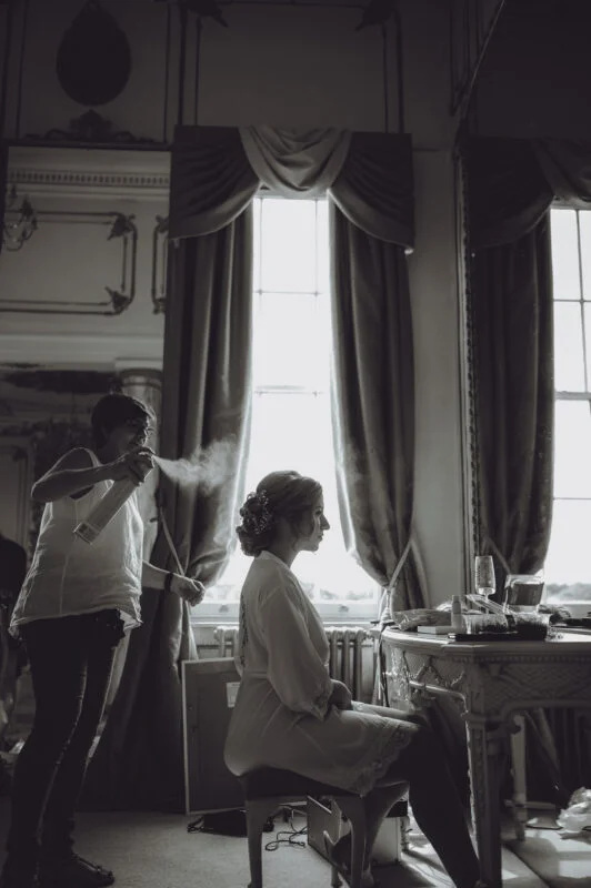 A bride getting ready in front of a mirror in a room.