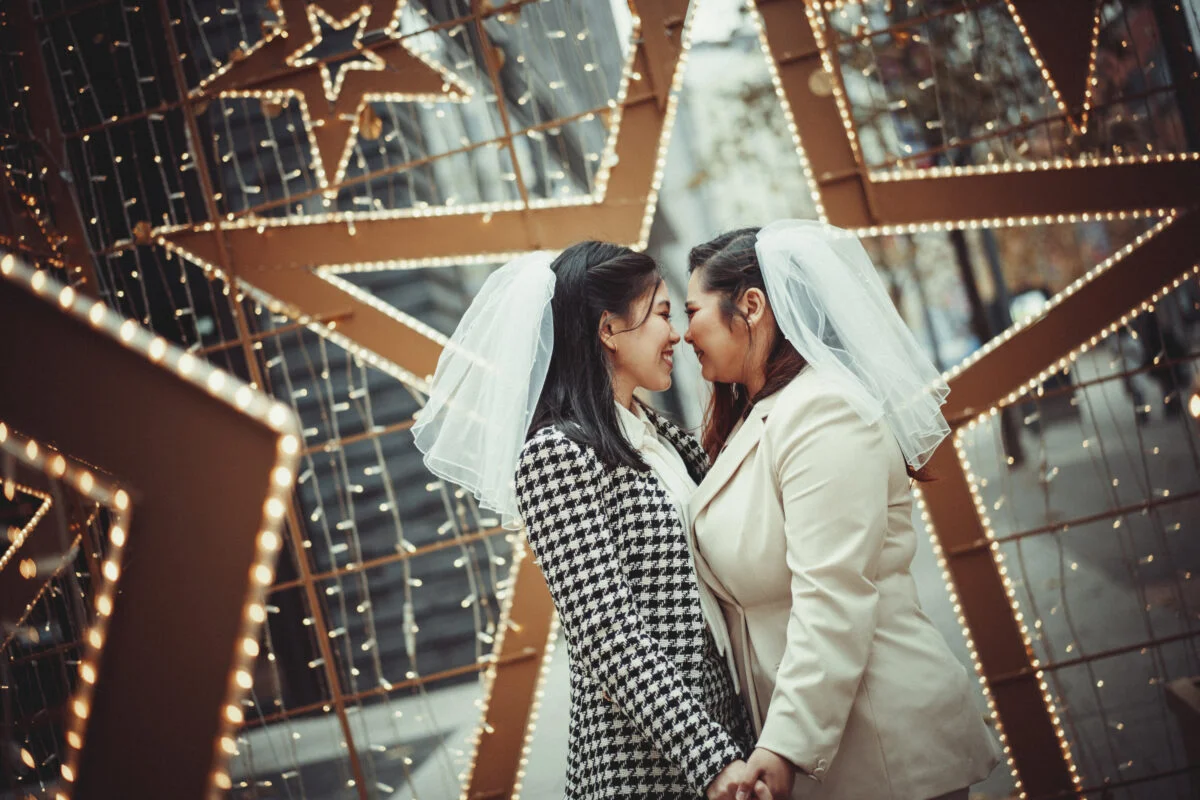 Two brides hugging in front of star lights.