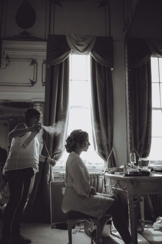 A bride getting ready in front of a mirror in a room.