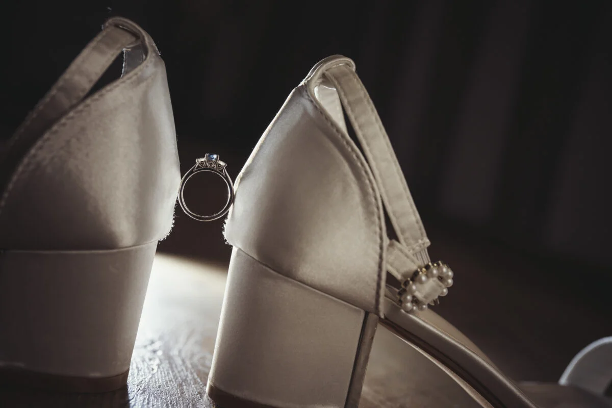 A pair of wedding shoes with a wedding ring on them.
