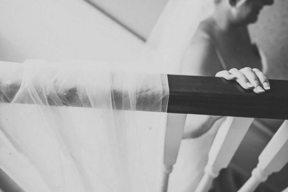A bride is holding her veil on a staircase.