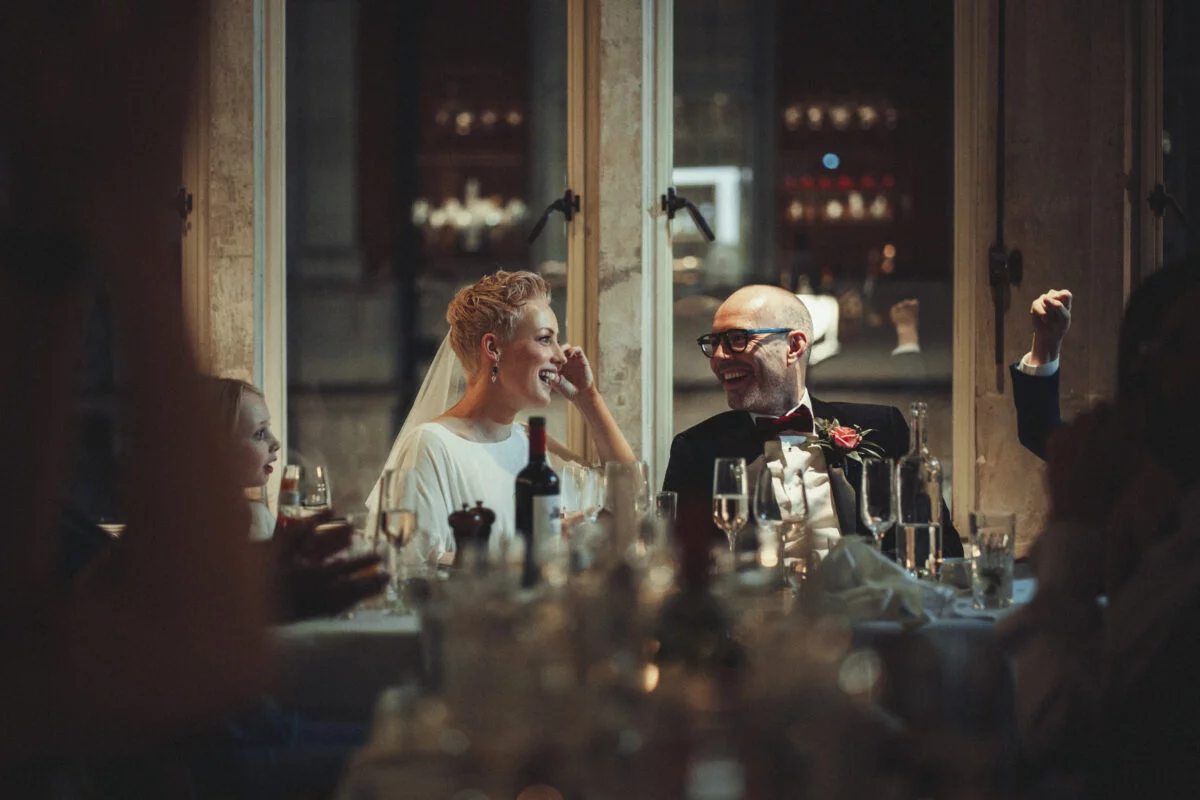 A bride and groom clapping at a wedding reception.