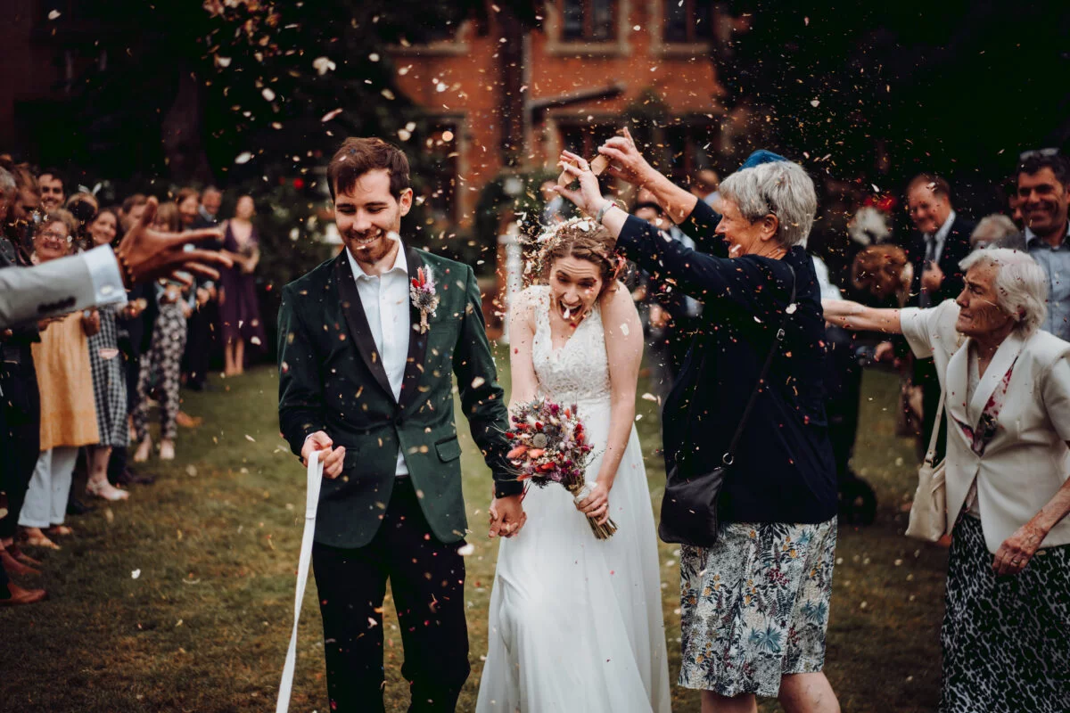 A bride and groom walking down the aisle with confetti thrown at them.