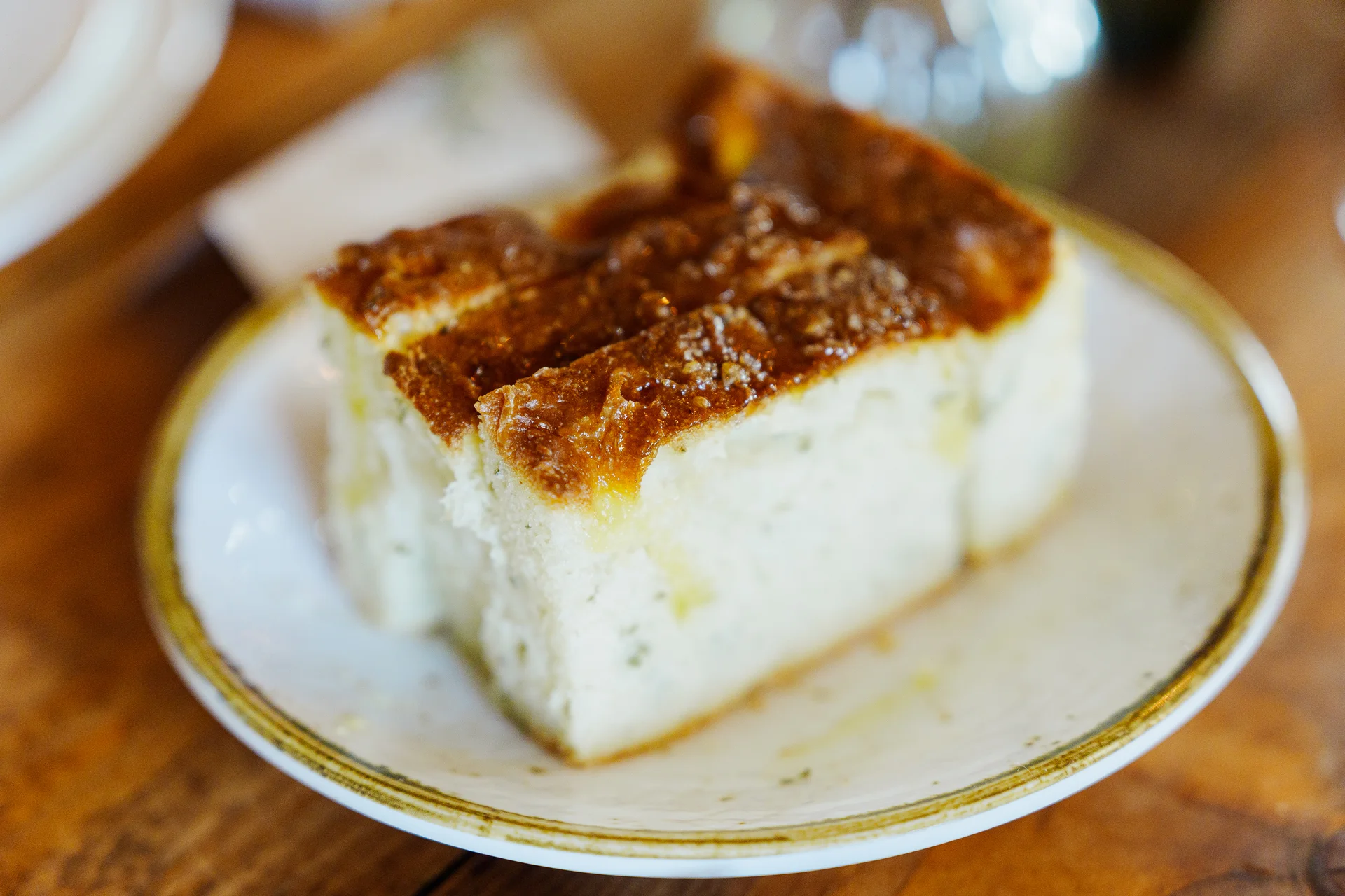 A close-up shot of a thick, golden slice of artisan bread served on a white ceramic plate during a wedding breakfast.