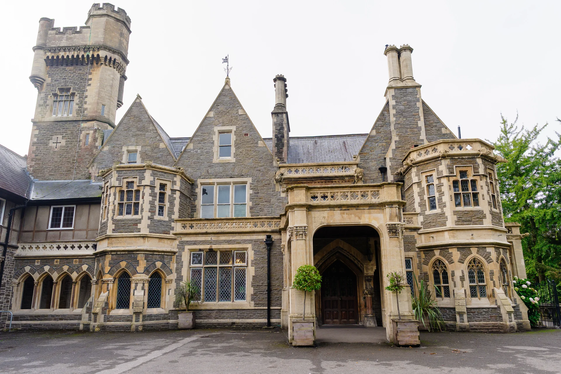 The grand stone exterior of a historic castle wedding venue featuring large arched entrances, detailed stonework and distinctive towers.