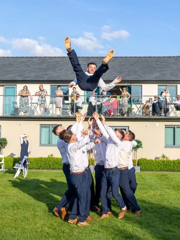 groomsmen lift groom in the air