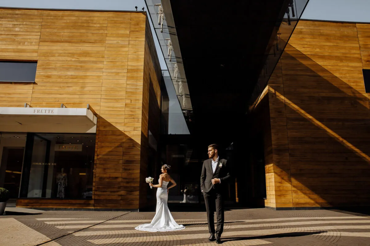 Bride and Groom Standing Apart in Front of Building