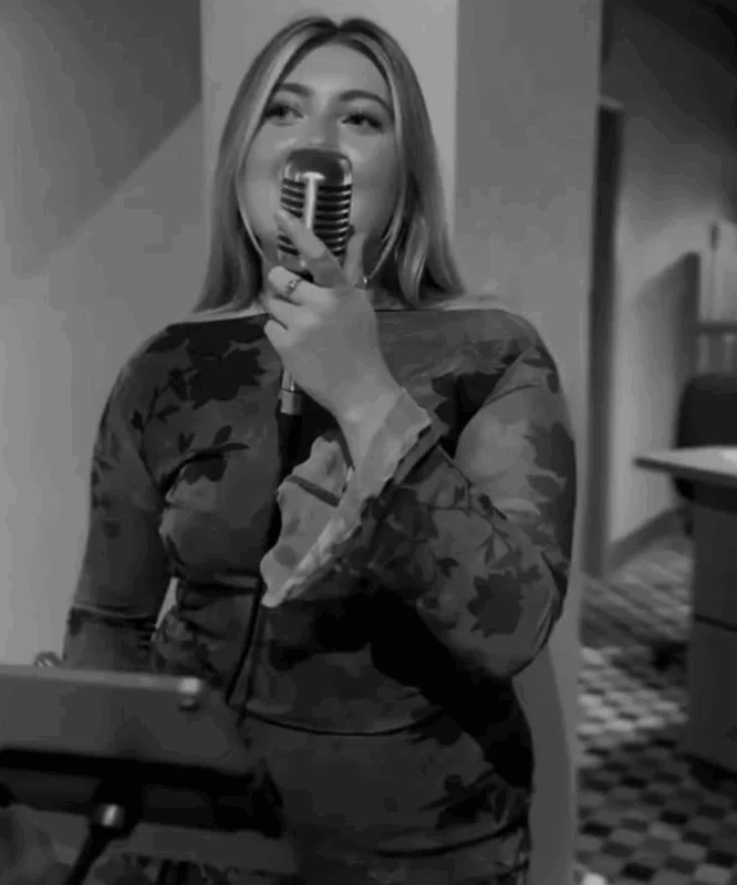 A joyful woman sings into a retro microphone during the wedding reception celebration.
