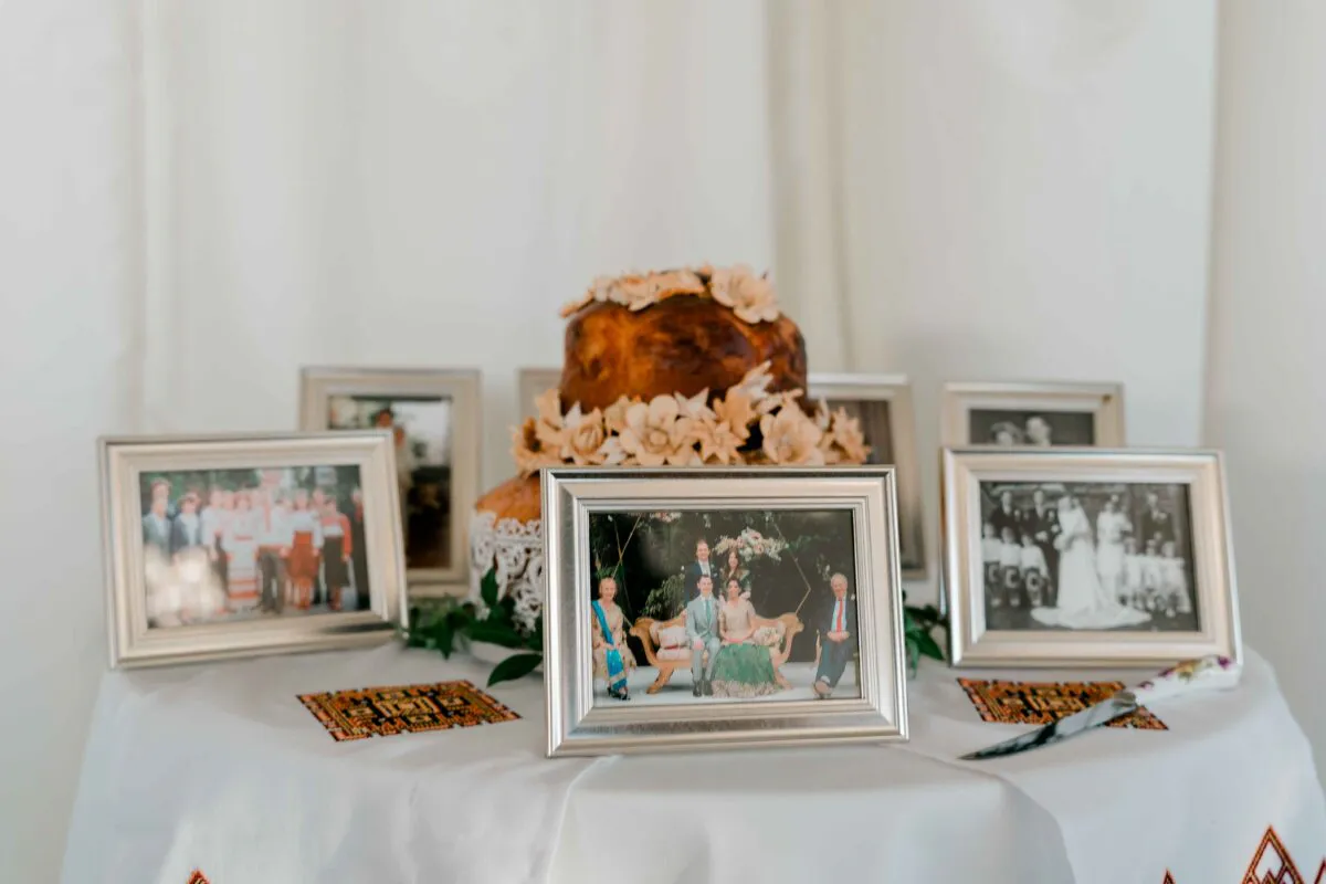 A traditional Polish wedding bread and salt display featuring decorated ceremonial bread surrounded by framed vintage family photographs on a white-linened table.