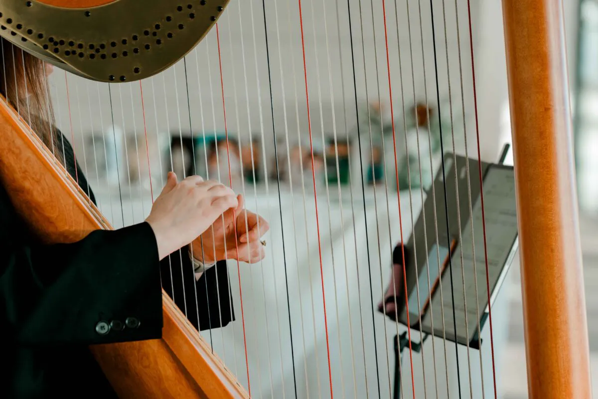 A close-up shot of a musician gracefully playing a wooden harp during a wedding ceremony.