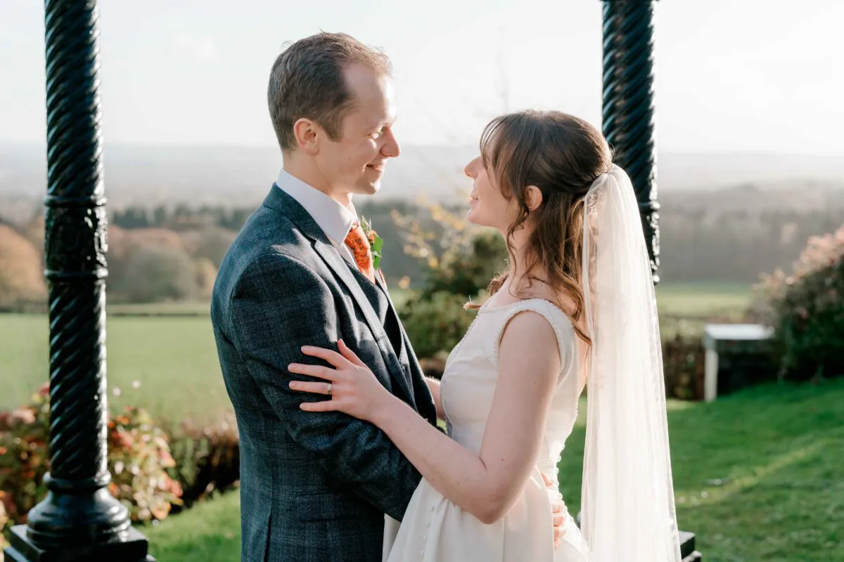A newlywed couple gazes lovingly at each other inside a scenic bandstand during their outdoor wedding portrait session.