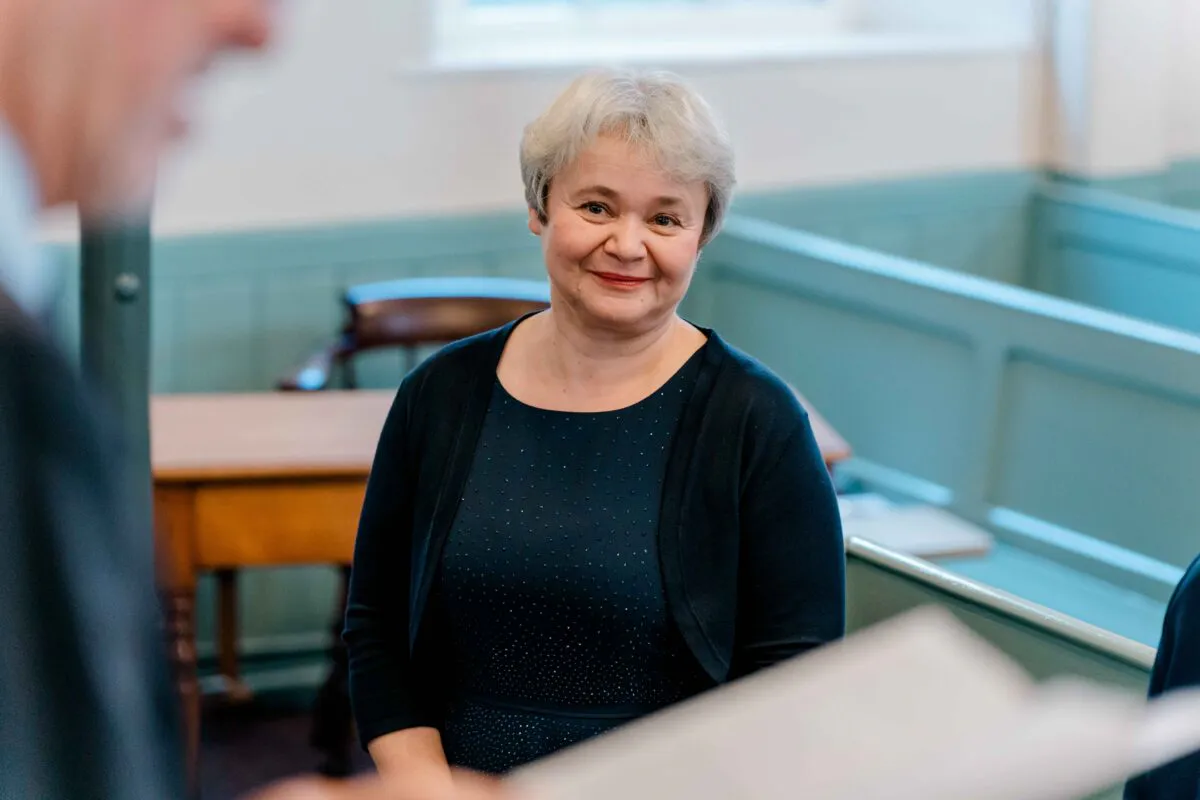 A mature bride with short grey hair smiles warmly during an intimate church wedding ceremony.