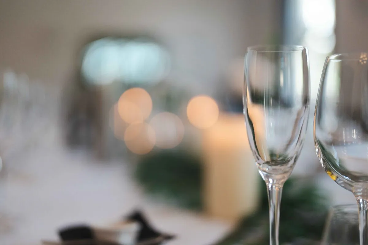 An elegant wedding tablescape features crystal glassware and soft candlelight glowing in the softly blurred background.